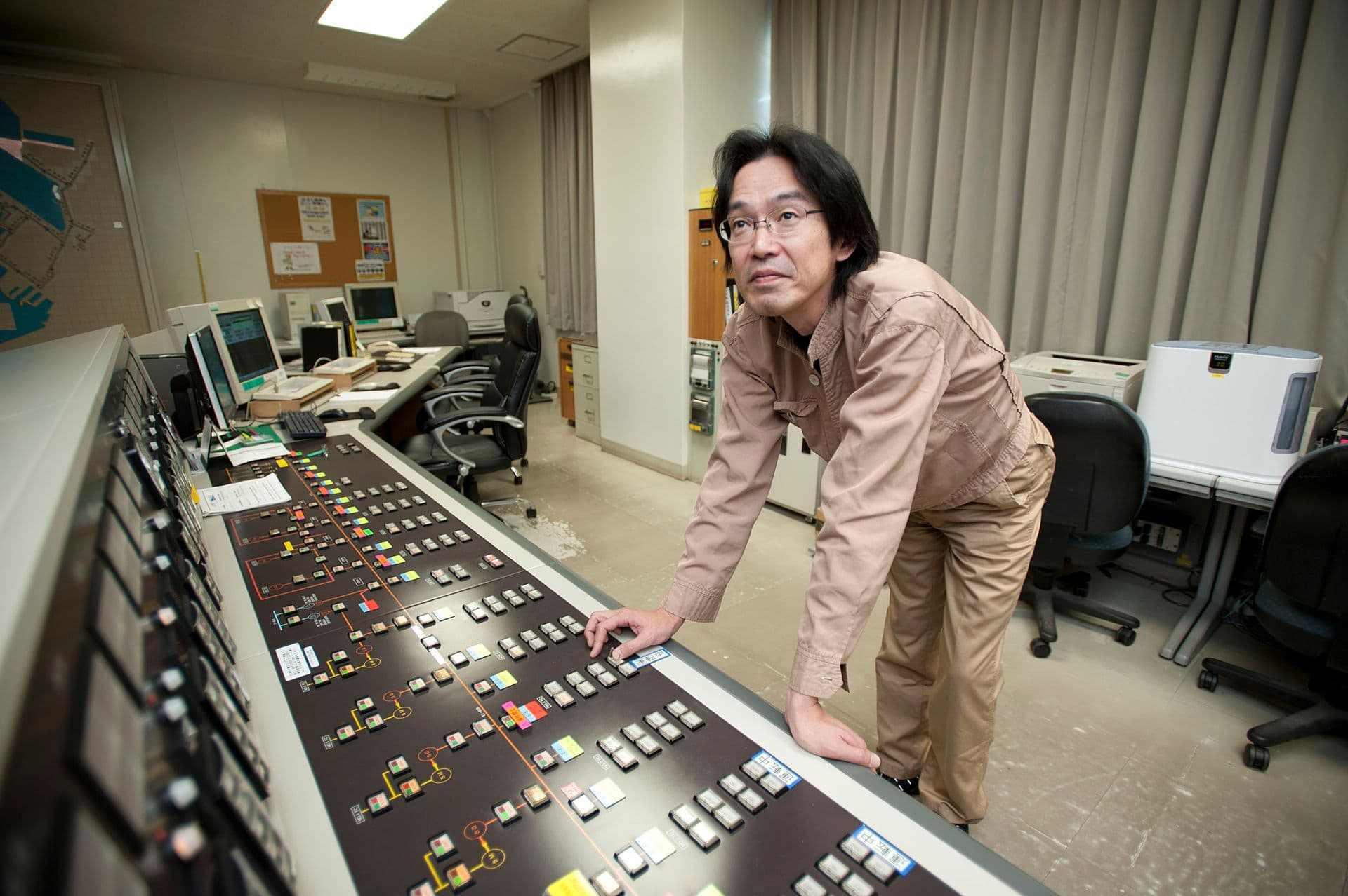 Operator at a SCADA console balancing an electrical load — supervisory control in action